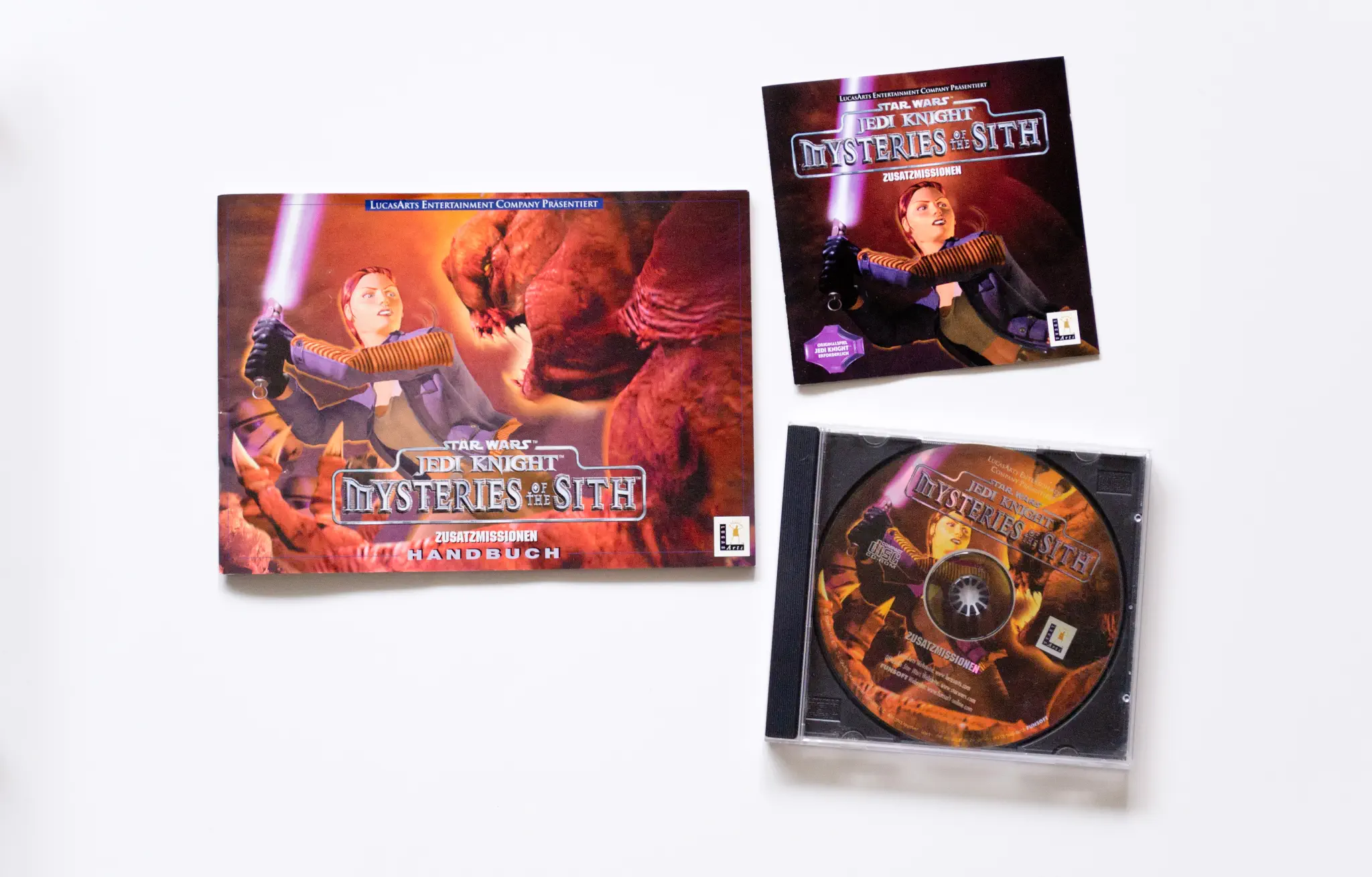 Photo of the content of Star Wars: Jedi Knight - Mysteries of the Sith (1998, PC, DE); developed by LucasArts Entertainment Company LLC, published by LucasArts Entertainment Company LLC; Hi-res 3D box available at https://bigboxcollection.com
